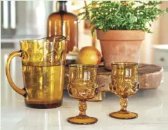  ?? ?? To achieve this farmhouse look, mix vintage items with new. While the cabinets and island are new, some of the accessorie­s, such as this amber glassware and vase set, are vintage. |ABOVE| A LITTLE VINTAGE CAN GO A LONG WAY. Kara hung a vintage strainer among a set of new copper pots from Riverbend. She also suggests displaying functional pieces such as this LeCreuset Dutch oven, also from Riverbend Home.