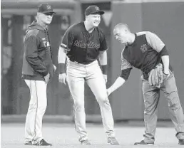  ?? TONY AVELAR/AP ?? Marlins right fielder Garrett Cooper grimaces as a trainer checks on him and manager Don Mattingly awaits informatio­n about what happened during Friday’s game.