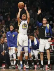  ?? FRANK FRANKLIN II — THE ASSOCIATED PRESS ?? Golden State Warriors react as teammate Stephen Curry shoots a three-point basket during the first half of an NBA basketball game against the Brooklyn Nets, Sunday in New York.