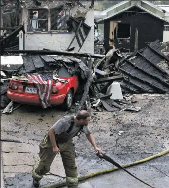  ?? The Sentinel-Record/Richard Rasmussen ?? AFTERMATH: Lake Hamilton volunteer firefighte­r Sam Clark works on wrapping up fire hoses after battling a blaze overnight at Four Seasons Villa Resort Sunday morning. The fire destroyed at least four townhomes and damaged multiple vehicles.