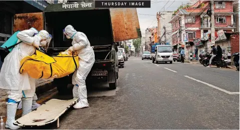  ??  ?? NEPALESE army personnel unload the body of a person who died of complicati­ons from infection with Covid-19, outside Pashupati Crematoriu­m in Kathmandu, Nepal, yesterday. | EPA