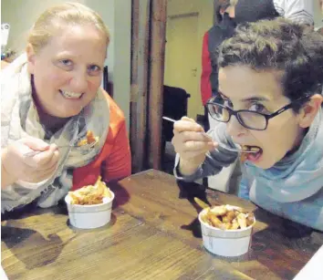  ?? —photo Gregg Chamberlai­n ?? Alissa Matthews (left) and Tara Pereira, both from Vermont, enjoyed their taste of genuine poutine from the St-Albert Cheese Factory. The two were part of the Canamex tour group of delegates from various government, business, and university groups from New York and Vermont states sampling local beverages and cuisine, as part of an internatio­nal food trail touring partnershi­p between the two states and the provinces of Ontario and Québec.