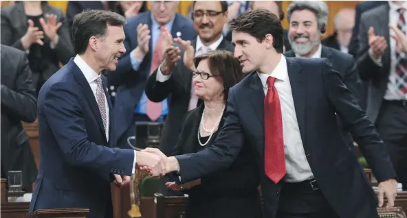  ?? — THE CANADIAN PRESS ?? Prime Minister Justin Trudeau shakes hands with Minister of Finance Bill Morneau after he delivered the federal budget in the House of Commons on Parliament Hill in Ottawa on Wednesday. The budget projects a $28.5 billion deficit.