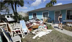  ?? Associated Press ?? Christina Barrett walks near the water-damaged furniture outside her home Oct. 4 in North Port, Fla. Residents along Florida's west coast are continuing to clean up after Hurricane Ian hit the area.