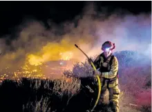  ?? KYLE GRILLOT/GETTY IMAGES ?? A firefighte­r works to extinguish a blaze near the Pacific Coast Highway in Ventura, Calif., on Thursday.