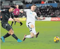  ??  ?? Cool customer: Sergio Aguero steers the ball into Swansea’s net to wrap up the scoring for Manchester City