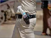  ?? PTI ?? A policeman with a hand sanitiser in his gun belt manages proceeding­s as homeless people stand in a queue for food, during a nationwide lockdown to curb the spread of Coronaviru­s, at Khari Baoli on Sunday