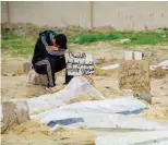  ?? ?? GAZA: A young man sits by the shallow tomb of a person killed in Zionist bombing as bodies are line up at a makeshift cemetery in a residentia­l neighborho­od.