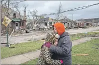  ??  ?? Residents Valerie McAvoy with daughter Jayda Weathersby, 9, hug as they survey tornado damage of their neighborho­od in Naplate, Ill., on Wednesday. Communitie­s across Illinois are cleaning up after deadly storms producing tornadoes moved through much...