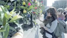  ?? — Reuters ?? A woman adds a flower to the tributes at the fence surroundin­g the House of Parliament, following the attack in Westminste­r earlier in the week, in London, on Saturday.