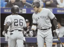  ?? AP PHOTO ?? WELCOME HOME: Andrew McCutchen (26) is congratula­ted by Aaron Judge after hitting a solo home run in the Yankees’ game against the Rays last night.