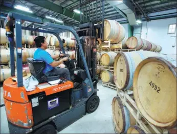  ?? BLOOMBERG ?? A forklift driver stacks oak barrels full of newly made wine at a production facility in Santa Rosa, California.