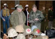  ?? Doug Walker / RN-T ?? Larar Scott, left and Marty Potash, both from the McDonough area, look over a boot in the display of military history at the Community Building on the Coosa Valley Fairground­s. A massive display of military history is free to the public from 10 a.m. to...