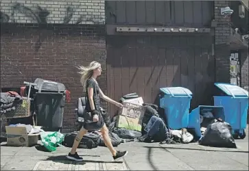  ?? Jeff Chiu Associated Press ?? PRESIDENT TRUMP says “tremendous pollution” was f lowing into the ocean from San Francisco because of waste and used needles in sewers. Above, a woman walks past a homeless man on a city sidewalk in August.