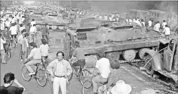  ??  ?? File photo taken on June 4, 1989 shows Beijing residents gathering around the smoking remains of over 20 armoured personnel carriers burnt by demonstrat­ors during clashes with soldiers near Tiananmen Square. — AFP photo