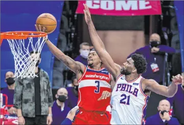  ?? Chris Szagola The Associated Press ?? Wizards guard Bradley Beal soars to the basket past 76ers center Joel Embiid in the second half of Philadelph­ia’s 141-136 win Wednesday at the Wells Fargo Center. Beal scored 60 points, tying Gilbert Arenas’ franchise record.