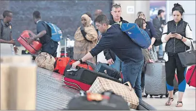  ?? CP PHOTO ?? Travellers pick up their luggage at a baggage carousel at the Ottawa Airport on Tuesday. The federal government is introducin­g legislatio­n for a passenger bill of rights that will set guidelines for how airlines passengers are treated.