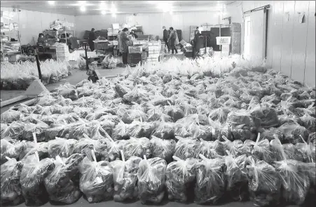  ?? WANG JING / CHINA DAILY ?? Vegetables are packed at Wuhan Baishazhou Agricultur­al Market in Hubei province on Wednesday. The largest agro-produce wholesale market in Central China, which remains open, ensures farm product supplies for Wuhan residents.