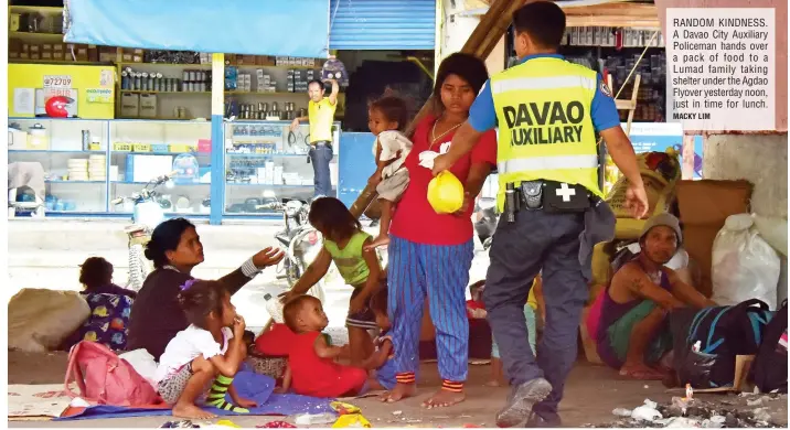  ?? MACKY LIM ?? RANDOM KINDNESS. A Davao City Auxiliary Policeman hands over a pack of food to a Lumad family taking shelter under the Agdao Flyover yesterday noon, just in time for lunch.