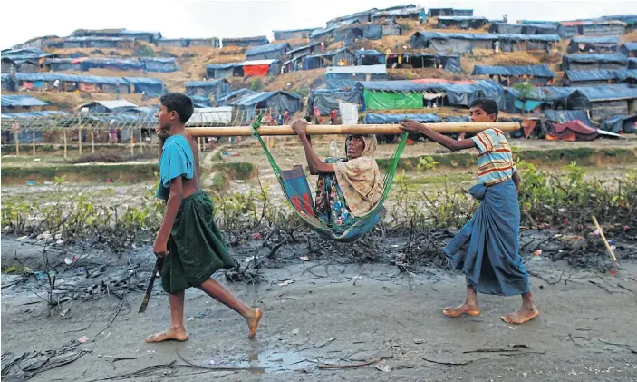  ??  ?? CARRYING A LOAD: Rohingya refugee children carry an old woman in a sling near a makeshift refugee camp in Cox’s Bazar, Bangladesh. In recent weeks, around 370,000 Rohingya have fled to Bangladesh.