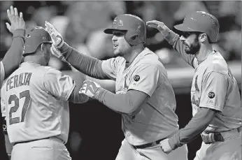  ?? Associated Press ?? St. Louis Cardinals Matt Holliday, center, is congratula­ted by teammates Jhonny Peralta (27) and Matt Carpenter after hitting a solo home run during the eighth inning of a baseball game against the Cleveland Indians on Tuesday in Cleveland.