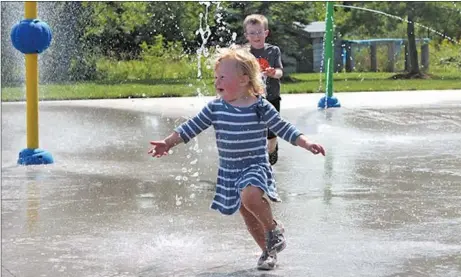  ?? AMANDA JESS/THE NEWS ?? Violet Little, 2, of Westville, and Matthew DeVouge, 4, of Greenhill, frolic in Westville’s new splash park during a test run. The park is set to open on Saturday at 11 a.m.