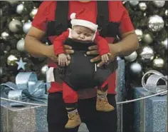  ?? Genaro Molina Los Angeles Times ?? JESSE AGUILAR, 2 months, gets some sleep while his father, Jesus, and other relatives take Christmas photos at Universal CityWalk.
