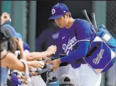 ?? Ashley Landis The Associated Press ?? Dodgers designated hitter Shohei Ohtani signs autographs for fans before making his spring training debut Tuesday.
