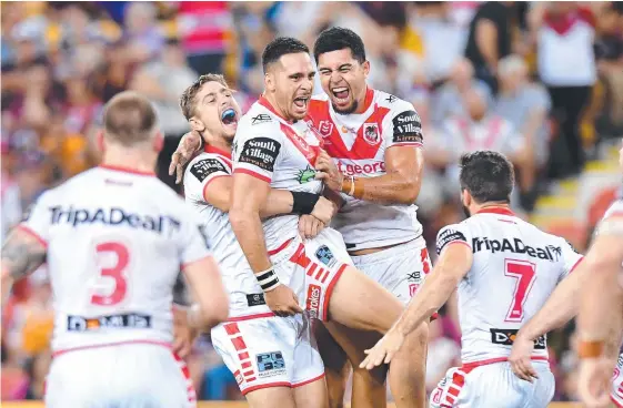  ?? Picture: GETTY IMAGES ?? Corey Norman is hugged by Dragons teammates after the Keebra product’s late field goal crushed the Broncos last night.