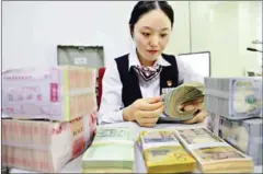  ?? SUPPLIED/CHINA DAILY ?? A cashier counts notes at a branch of Bank of China.