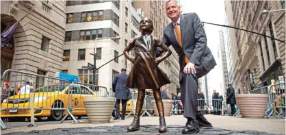  ??  ?? New York City Mayor Bill De Blasio poses for a photo with the 'Fearless Girl' statue during a press availabili­ty in New York City. — AFP