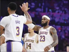  ??  ?? Los Angeles Lakers forward LeBron James congratula­tes forward Anthony Davis during a timeout in the first half of the team’s preseason NBA basketball game against the Golden State Warriors on Oct. 16, in Los Angeles. AP PHOTO/MARK J. TERRILL