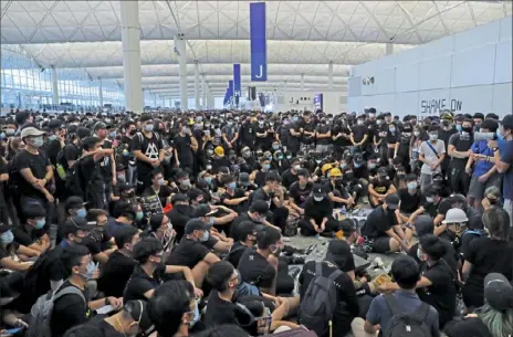  ?? Kin Cheung/ Associated Press ?? Protesters gather near an informatio­n board during a protest Monday at the Hong Kong Internatio­nal Airport. One of the world’s busiest airports canceled all flights after thousands of Hong Kong pro- democracy protesters crowded into the main terminal Monday afternoon.