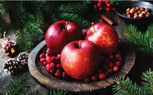  ?? GETTY IMAGES ?? Red apples, cranberrie­s and fir tree branches make a charming alternativ­e to the traditiona­l floral centrepiec­e.