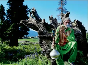  ??  ?? A Gujjar man sits and smokes his hookah in Nagin village. The Gujjars stay in Baramullah during the winter and return to their painted huts in Nagin every May when the snow melts