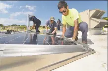  ??  ?? ENCON employees, including C. J. Pappas, left, install solar panels on the roof of the Paul Miller Nissan dealership.