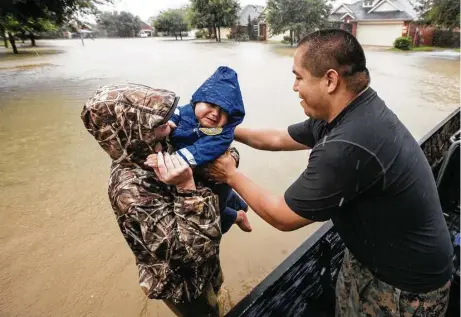  ?? Brett Coomer / Houston Chronicle ?? Wilfredo Linares reaches for his baby, Mason, as they are evacuated from the Grand Mission subdivisio­n Monday in Fort Bend County.