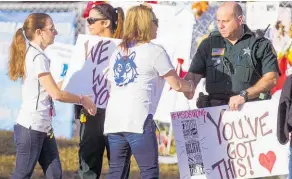  ?? Picture / AP ?? Staff and police welcome students as they arrive at Marjory Stoneman Douglas High yesterday.