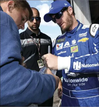  ?? AP PHOTO/NICK WASS ?? Dale Earnhardt Jr. (right) signs for a fan before practice for the NASCAR Cup series auto race, Saturday, at Dover Internatio­nal Speedway in Dover, Del.