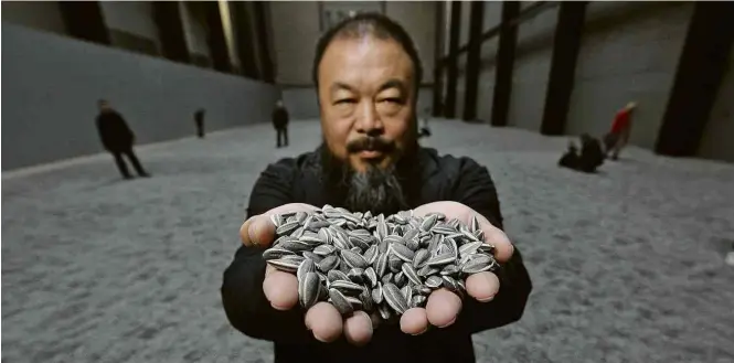  ?? Peter Macdiarmid/ Getty Images ?? Ai Weiwei segura sementes de porcelana na instalação ‘Sunflower Seeds’, em Londres; obra estará em mostra no Brasil