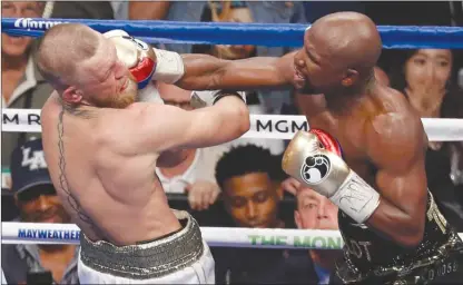 ?? The Associated Press ?? Floyd Mayweather Jr. connects with a punch on Conor McGregor during their super-welterweig­ht boxing match on Saturday night in Las Vegas. Mayweather won by technical knockout when the referee stopped the fight in the 10th round.