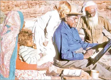  ??  ?? Photo shows family members watching Namatjira sitting on a rock as he paints. — Reuters photo