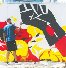  ?? JASON PAYNE ?? Sarbjot Atwal works on a mural in Whalley, Surrey on Thursday, saying he finds the creative process “mellow and soothing.”