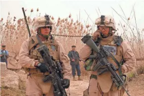  ?? MEG JONES/MILWAUKEE JOURNAL SENTINEL ?? Cpl. Jose Gonzalez, 24, of Kenosha (right), talks on a radio carried by Lance Cpl. Terry Medema, 24, of Waupun, in 2008 in Iraq. Gonzalez was calling his commander to tell him that Iraqi police officers had discovered two 67-millimeter rockets on a bank of the Euphrates River near Hamimiyah in Anbar Province.