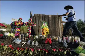  ?? ERIC GAY — THE ASSOCIATED PRESS ?? Roberto Marquez of Dallas adds a flower a make-shift memorial at the site where officials found dozens of people dead in an abandoned semitraile­r containing suspected migrants June 29in San Antonio.