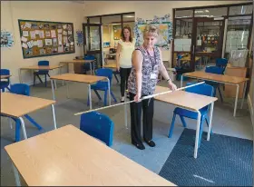  ?? (AP/Jon Super) ?? Teacher Jane Cooper uses a ruler and pipe to check seat spacings in her classroom Wednesday as measures are taken to prevent the transmissi­on of coronaviru­s before the possible reopening of Lostock Hall Primary school in Poynton near Manchester, England.