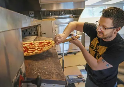  ?? Steve Mellon/Post-Gazette photos ?? Josh Sickels slides a pizza out of the oven at Rockaway Pizzeria in White Oak.