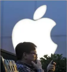  ?? NG HAN GUAN — THE ASSOCIATED PRESS FILE ?? In this file photo, a man uses his mobile phone near an Apple store in Beijing.