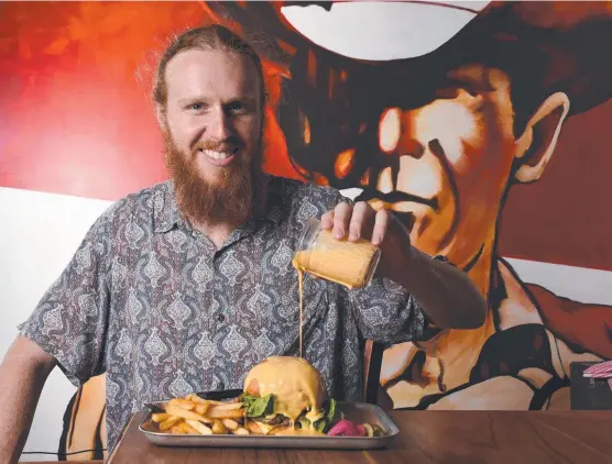  ?? Picture: STEVE HOLLAND ?? Barman Luke Kelly with Lester and Earl's cheeseburg­er with its secret-method melted cheese.