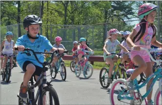  ?? LAUREN HALLIGAN - MEDIANEWS GROUP ?? Children in the Milton Summer Camp program wear their helmets while biking on Wednesday at Burgess Kimball Memorial Park as part of the Safe Summer Bike Helmet Safety Program kick-off event.